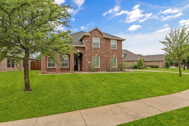 traditional home with brick siding, a shingled roof, fence, and a front yard