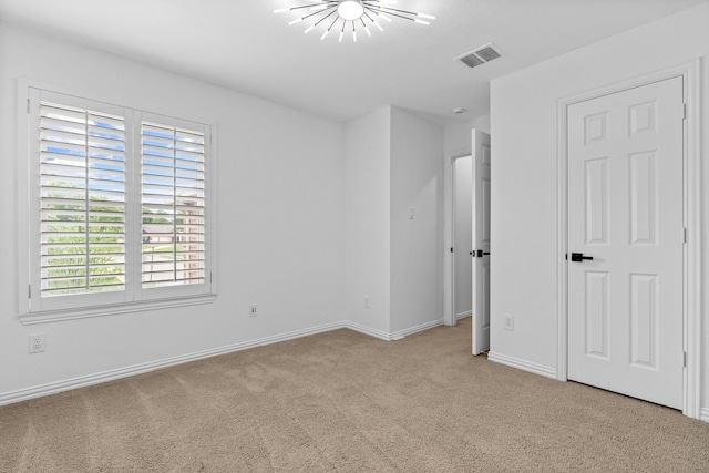 unfurnished bedroom with visible vents, carpet flooring, baseboards, and an inviting chandelier