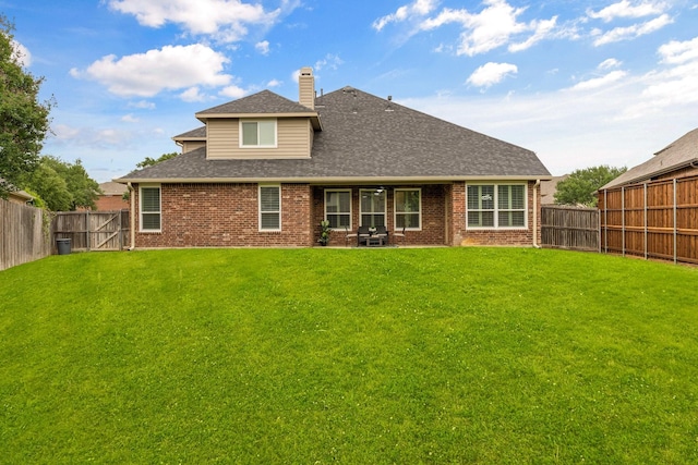 rear view of property with brick siding, a fenced backyard, a yard, and a chimney