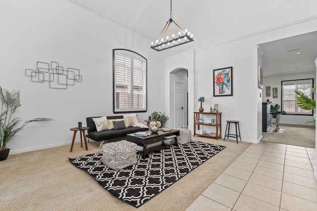 tiled living room featuring an inviting chandelier, a towering ceiling, baseboards, arched walkways, and carpet