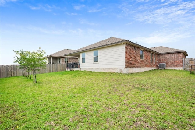 rear view of house featuring a fenced backyard, central AC unit, a yard, and brick siding