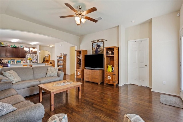 living area with visible vents, dark wood-style flooring, baseboards, arched walkways, and ceiling fan with notable chandelier