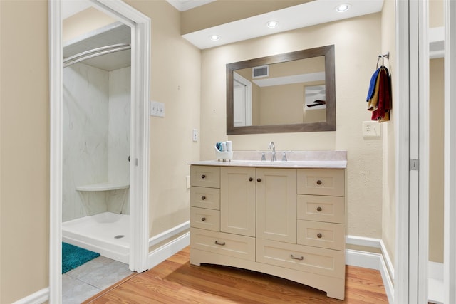 full bath featuring vanity, a shower stall, wood finished floors, and visible vents