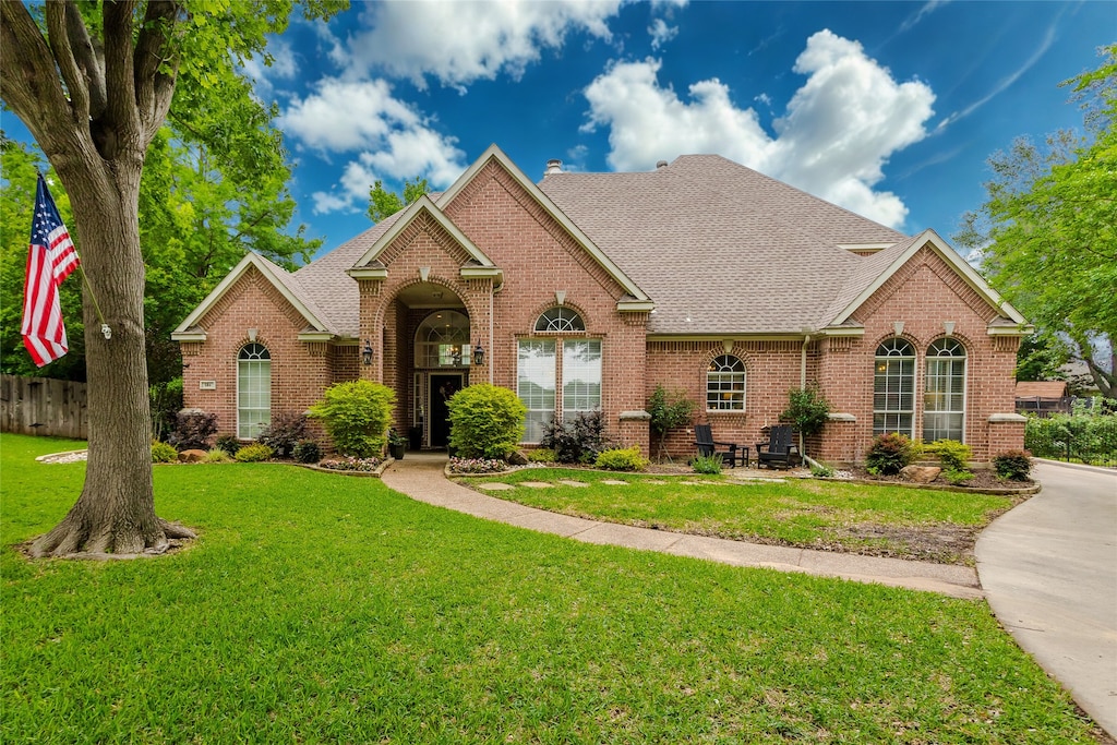 single story home with brick siding, fence, a front yard, and roof with shingles