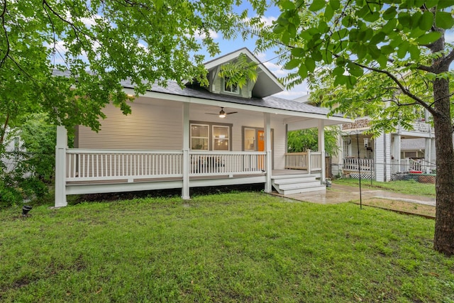 farmhouse-style home featuring a front lawn, ceiling fan, fence, covered porch, and a shingled roof