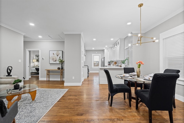 dining room with light wood-style floors, ornamental molding, baseboards, and recessed lighting