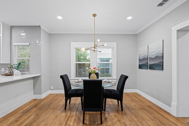 dining area featuring crown molding, a chandelier, a healthy amount of sunlight, and wood finished floors