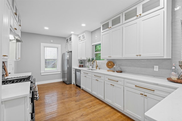 kitchen with white cabinetry, tasteful backsplash, a sink, appliances with stainless steel finishes, and a wealth of natural light
