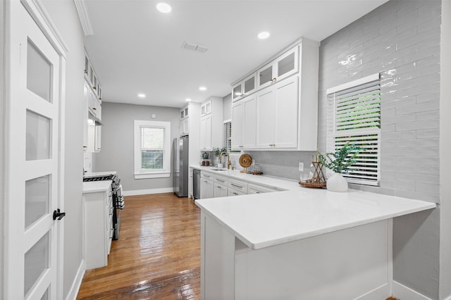 kitchen featuring a sink, baseboards, light countertops, glass insert cabinets, and stainless steel appliances