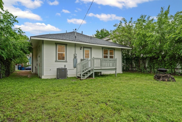 back of house with fence, a shingled roof, an outdoor fire pit, cooling unit, and a yard