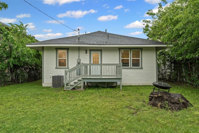 rear view of house featuring a yard, a shingled roof, cooling unit, and an outdoor fire pit