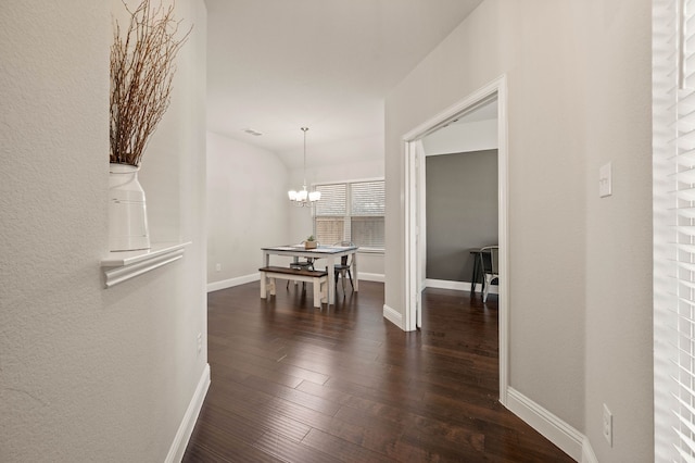 hallway with baseboards, dark wood finished floors, visible vents, and an inviting chandelier