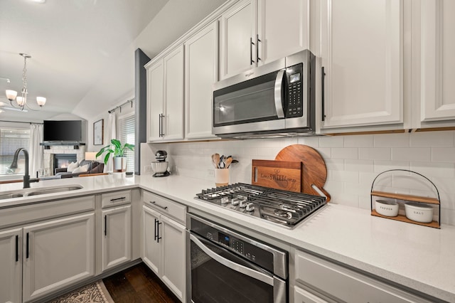 kitchen with a sink, tasteful backsplash, vaulted ceiling, and stainless steel appliances