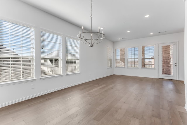 unfurnished dining area with baseboards, recessed lighting, wood finished floors, and a notable chandelier