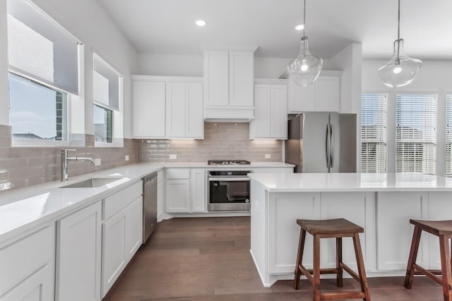 kitchen with a breakfast bar area, stainless steel appliances, white cabinets, and a sink
