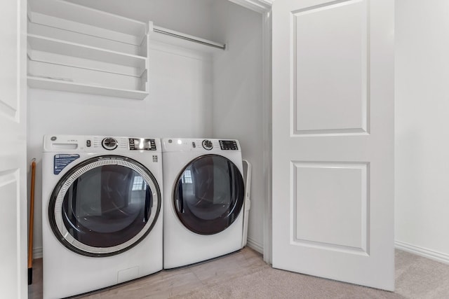 clothes washing area with laundry area, washer and clothes dryer, and baseboards