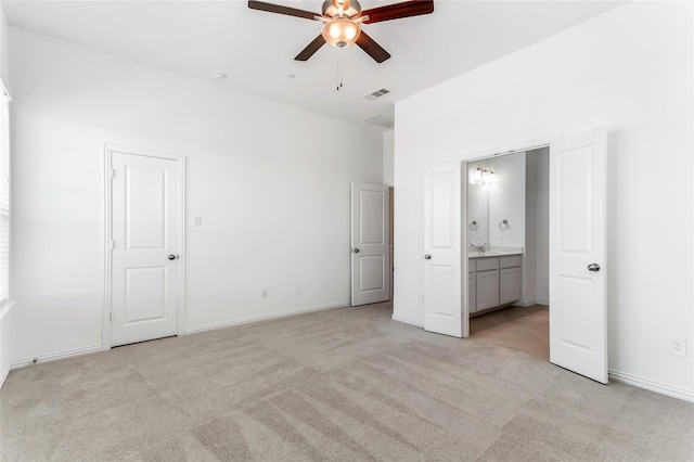 unfurnished bedroom with light carpet, a sink, ensuite bath, baseboards, and visible vents