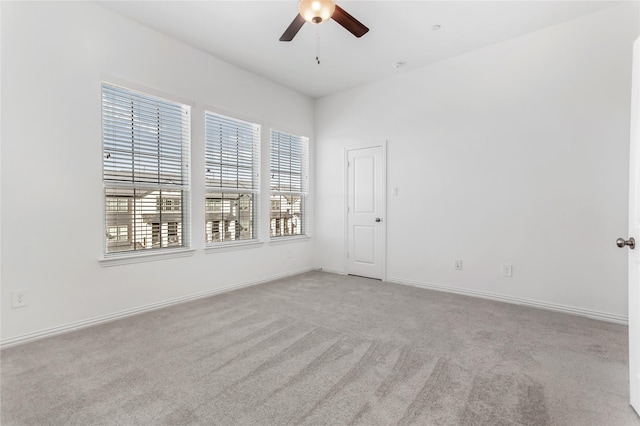 empty room featuring ceiling fan, light colored carpet, and baseboards