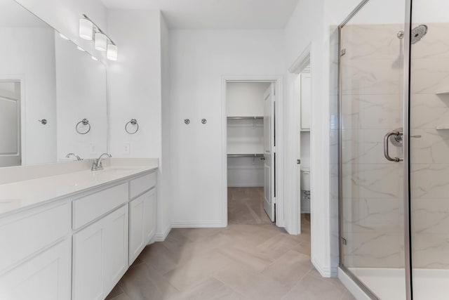 full bathroom featuring vanity, a marble finish shower, and a spacious closet