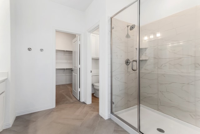 bathroom with baseboards, a marble finish shower, and toilet