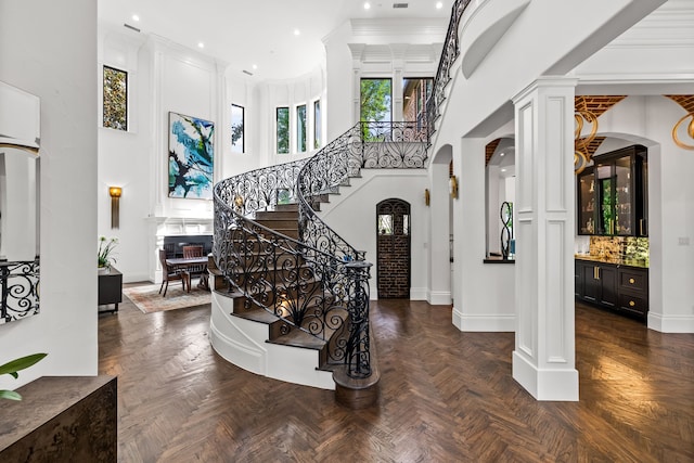 entrance foyer with ornate columns, baseboards, stairway, and a towering ceiling