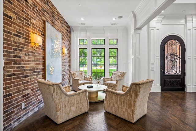 living area with crown molding, a decorative wall, brick wall, recessed lighting, and visible vents