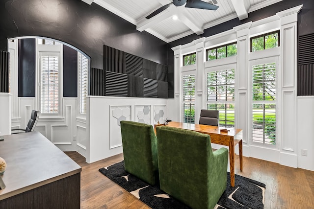 dining area with beamed ceiling, a ceiling fan, a decorative wall, and wood finished floors