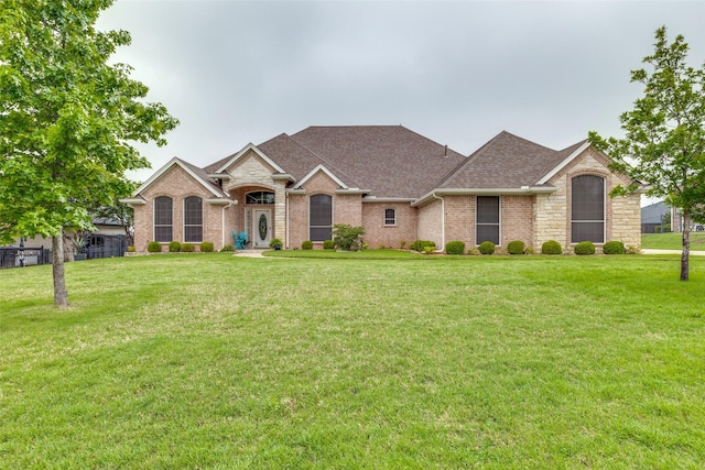 ranch-style house with brick siding, a shingled roof, and a front yard