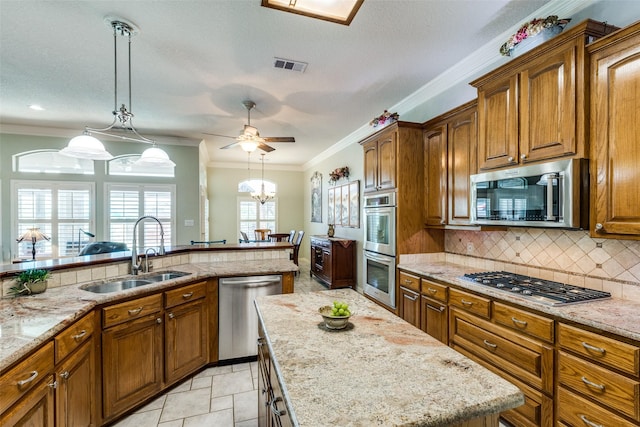 kitchen with brown cabinets, appliances with stainless steel finishes, a sink, decorative backsplash, and visible vents