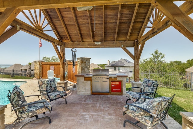 view of patio / terrace featuring a fenced in pool, a fenced backyard, grilling area, and an outdoor kitchen
