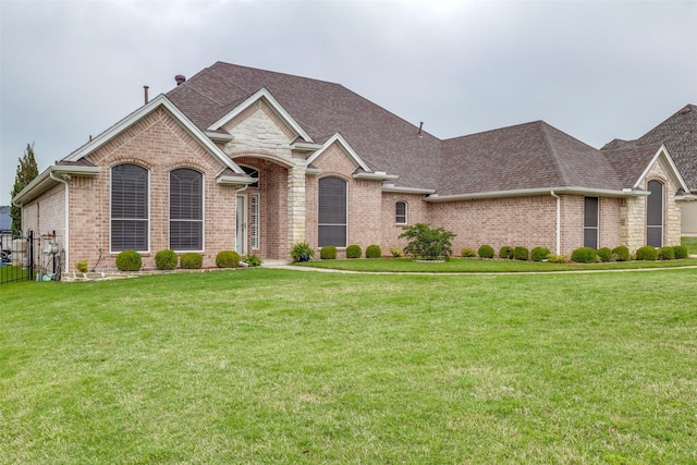 view of front facade featuring brick siding, a front yard, and roof with shingles