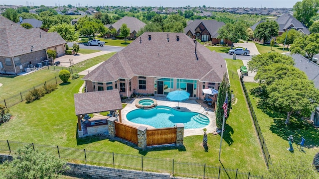 view of pool featuring a lawn, a pool with connected hot tub, a fenced backyard, and a residential view