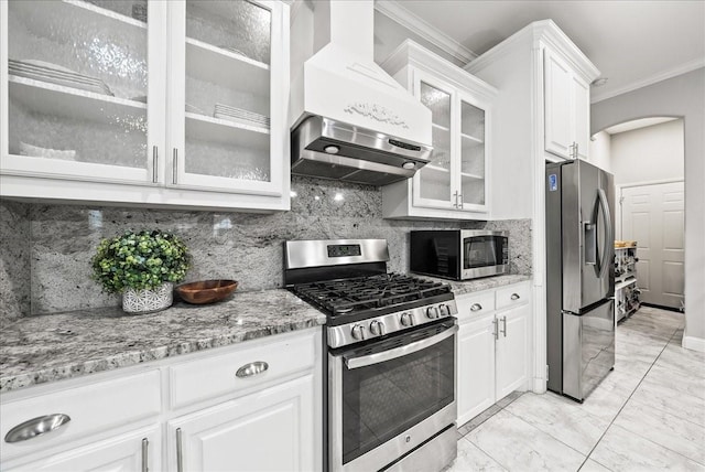 729 Rockwood St, Dallas, TX 75203 - kitchen featuring appliances with stainless steel finishes, exhaust hood, crown molding, arched walkways, and light marble finish flooring