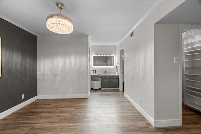 interior space featuring crown molding, a chandelier, baseboards, wood finished floors, and visible vents