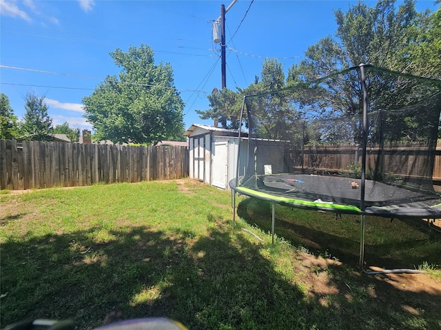 view of yard featuring a storage unit, a fenced backyard, a trampoline, and an outdoor structure
