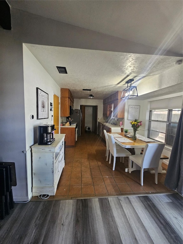 dining room featuring visible vents, a textured ceiling, and dark wood-type flooring