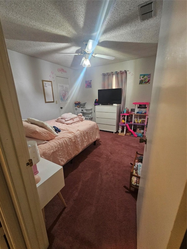 carpeted bedroom with visible vents, a ceiling fan, and a textured ceiling