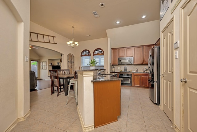 kitchen with backsplash, arched walkways, light tile patterned floors, lofted ceiling, and stainless steel appliances