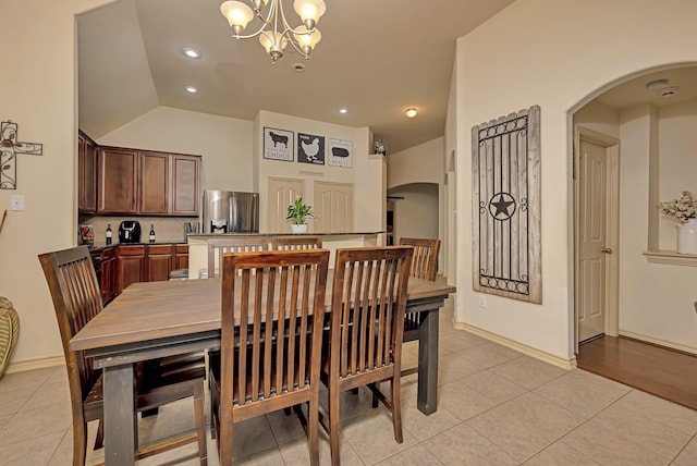 dining area featuring a chandelier, arched walkways, light tile patterned floors, lofted ceiling, and recessed lighting