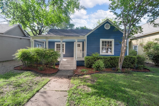 view of front of property with covered porch, roof with shingles, and a front lawn