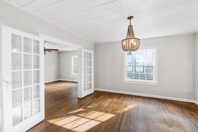 unfurnished dining area with baseboards, wood finished floors, a notable chandelier, and french doors