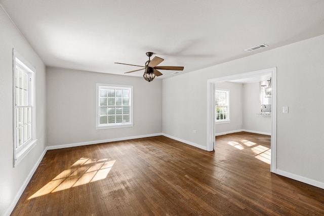 unfurnished room with baseboards, visible vents, a healthy amount of sunlight, and hardwood / wood-style flooring
