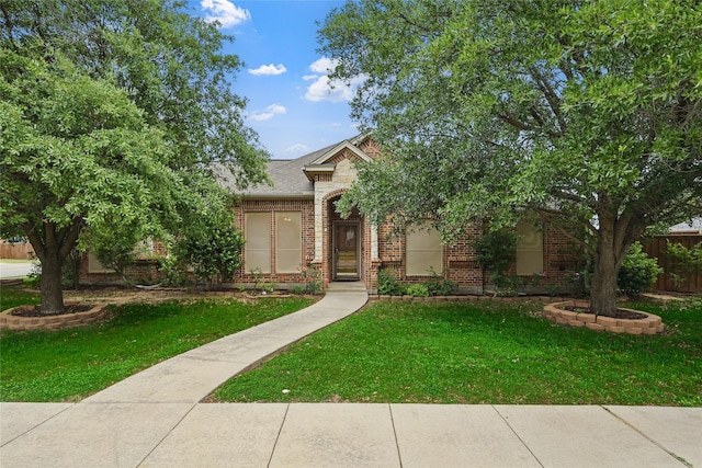 view of front of property featuring brick siding, fence, and a front yard