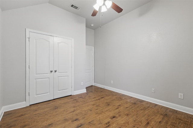unfurnished bedroom with baseboards, lofted ceiling, wood finished floors, and visible vents