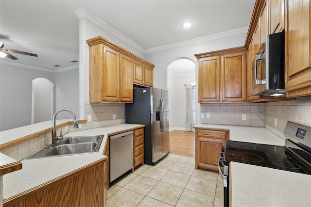 kitchen featuring crown molding, light tile patterned flooring, a sink, arched walkways, and stainless steel appliances