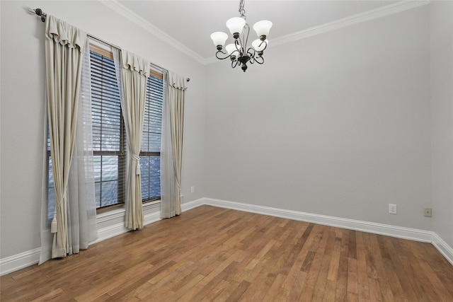 empty room with baseboards, an inviting chandelier, ornamental molding, and wood finished floors