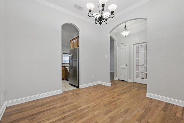 unfurnished dining area featuring visible vents, arched walkways, baseboards, ornamental molding, and light wood-style flooring