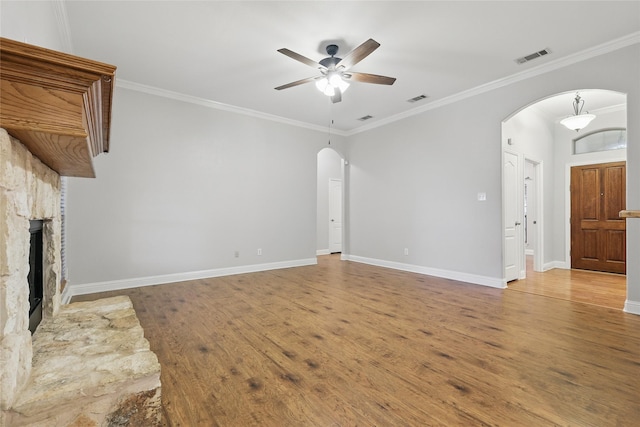 unfurnished living room with arched walkways, a ceiling fan, wood finished floors, and visible vents