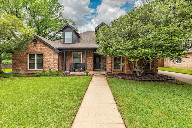 view of front of home featuring brick siding, a front lawn, roof with shingles, and covered porch