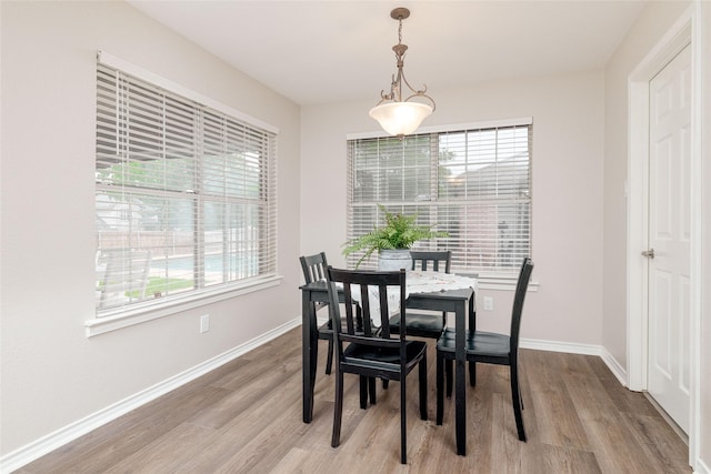 dining space with baseboards and light wood-type flooring